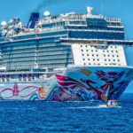 A colorful cruise ship sailing on the open sea under a clear blue sky. Ideal for tourism and travel themes.