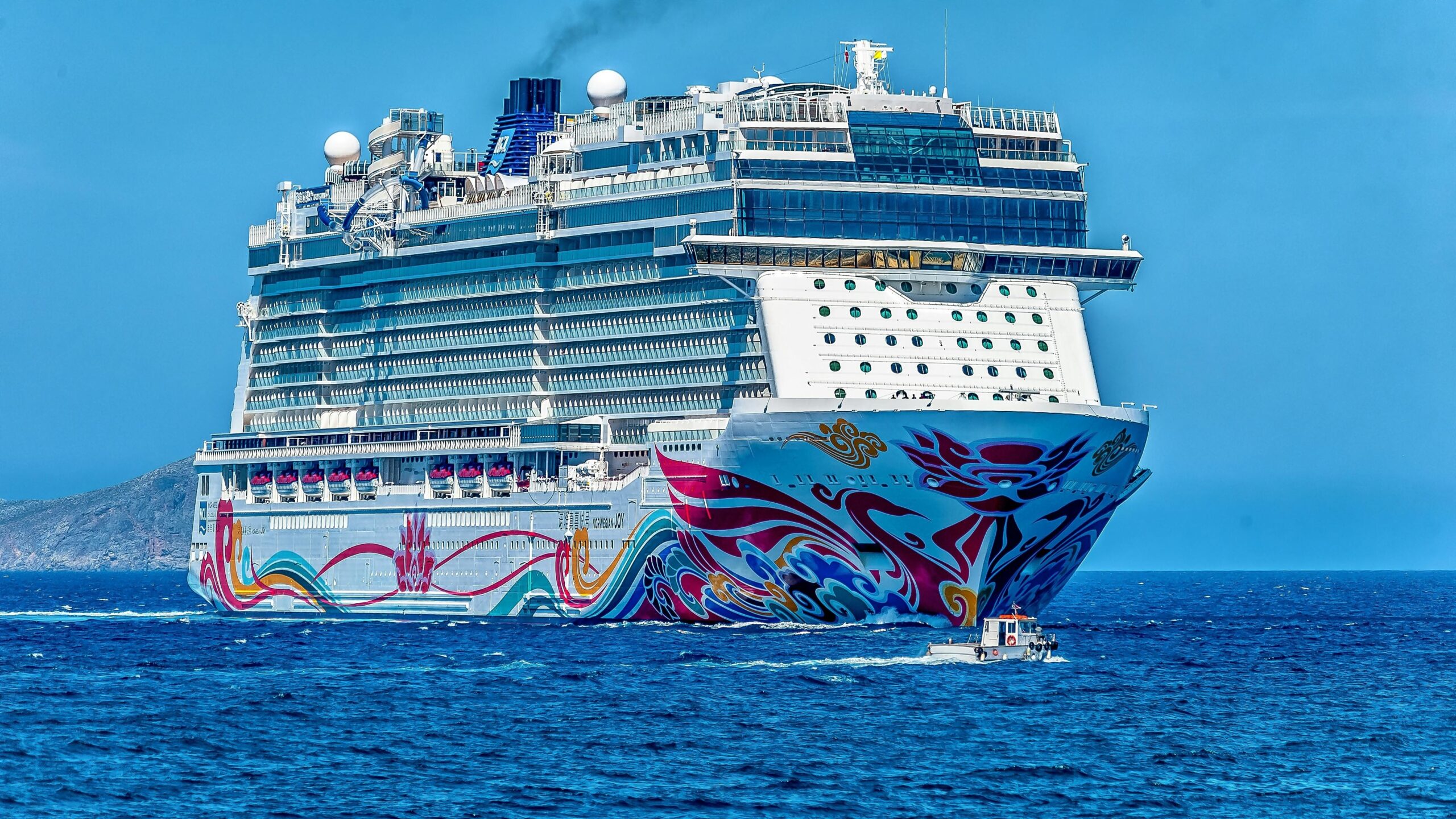 A colorful cruise ship sailing on the open sea under a clear blue sky. Ideal for tourism and travel themes.